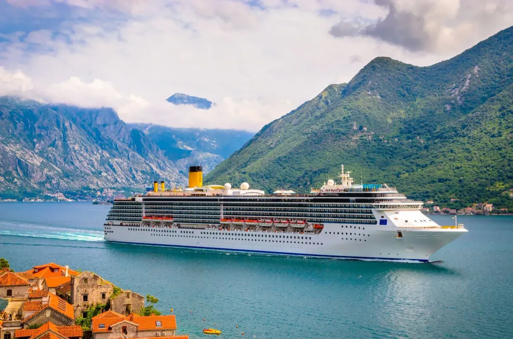 Cruise ship in water in front of lush green mountains